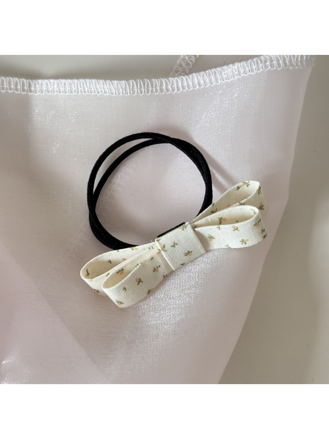 Gifty bow embellished hair tie displayed flat with elastic band visible