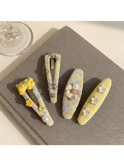 Close-up of yellow floral hair clip showing detailed fabric texture and flower pattern