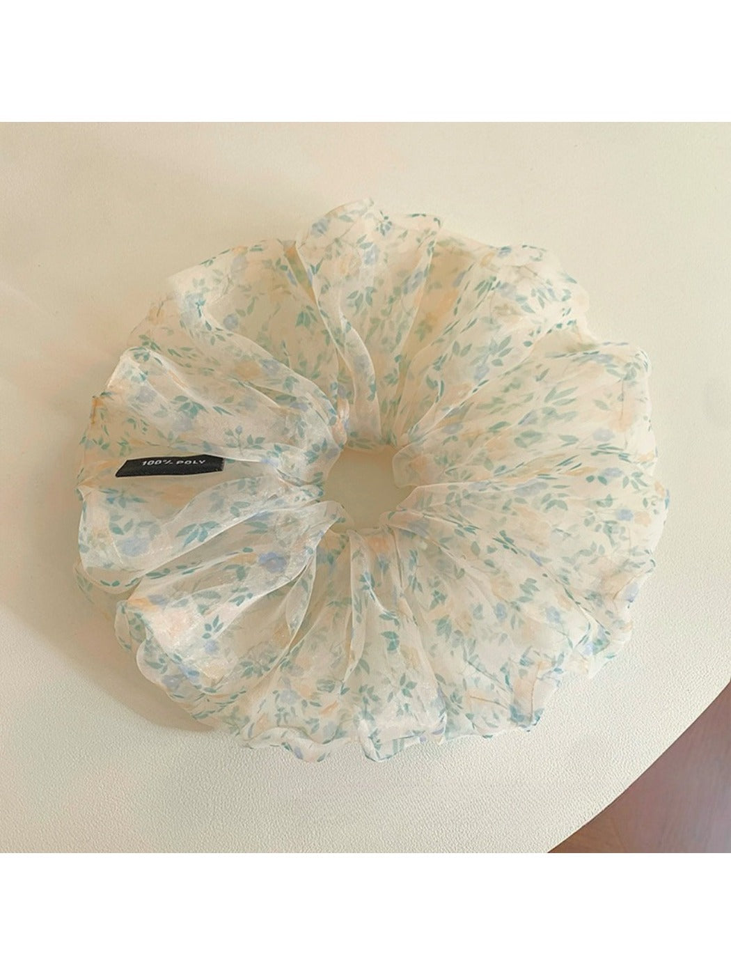 Green floral scrunchie stretched to show elastic band inside