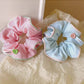 Gifty scrunchie displayed next to matching hair clips on a wooden surface