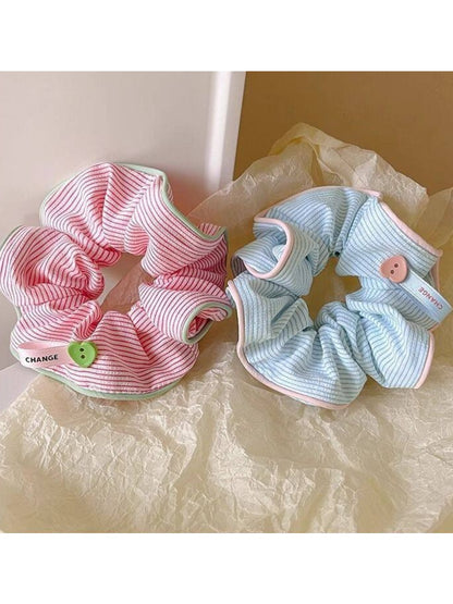 Gifty scrunchie displayed next to matching hair clips on a wooden surface