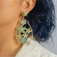 Earedge floral raffia drop earrings displayed hanging on a jewelry stand