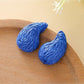 Top view of raffia water drop shaped stud earrings highlighting woven details