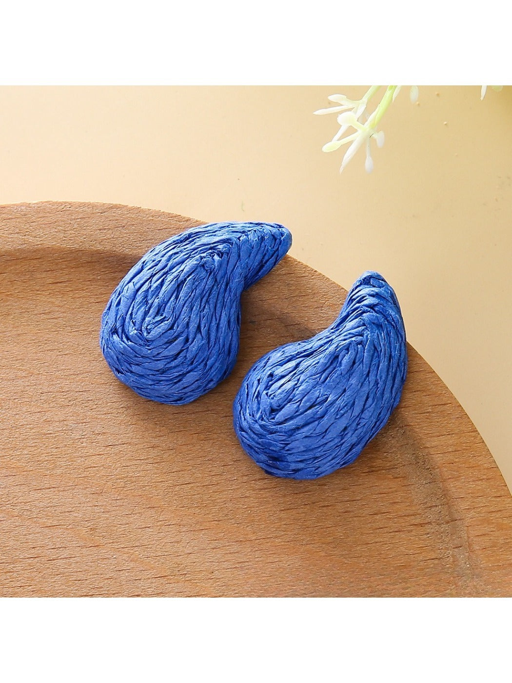Top view of raffia water drop shaped stud earrings highlighting woven details