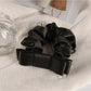 Soft fabric scrunchie with gentle gathers and romantic floral charm detail