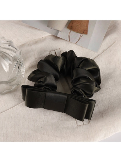 Soft fabric scrunchie with gentle gathers and romantic floral charm detail