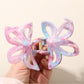 Beau hair clip clipped onto brown hair, displaying colorful flower design