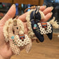 Fabric pony keychain hanging from a handbag strap