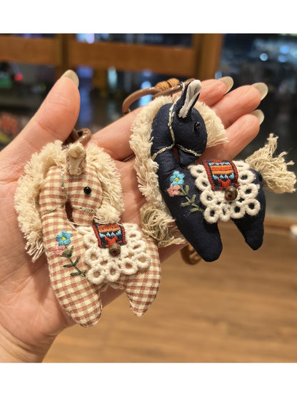 Fabric pony keychain hanging from a handbag strap