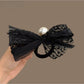 Close-up of the satin bow on the black hair tie showing pearl embellishments