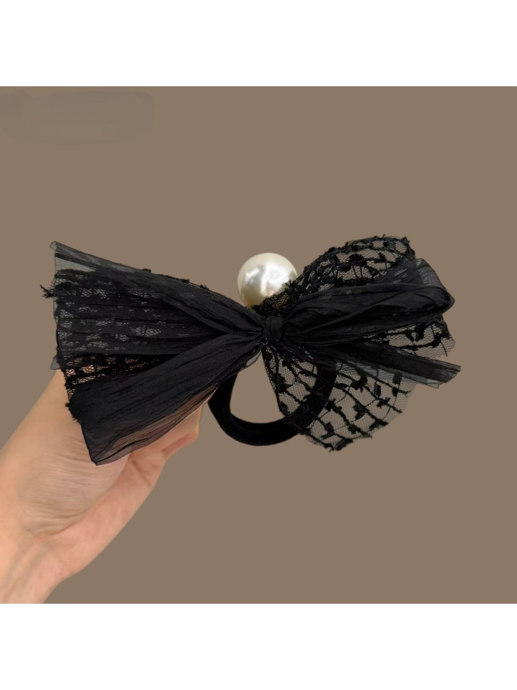 Close-up of the satin bow on the black hair tie showing pearl embellishments