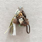 Fabric doll keychain displayed on a wooden surface with vibrant curly hair
