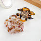 Beau hair claw clip displayed on a wooden surface with natural lighting