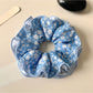 Blue floral pattern scrunchie with pastel colors and gathered fabric design