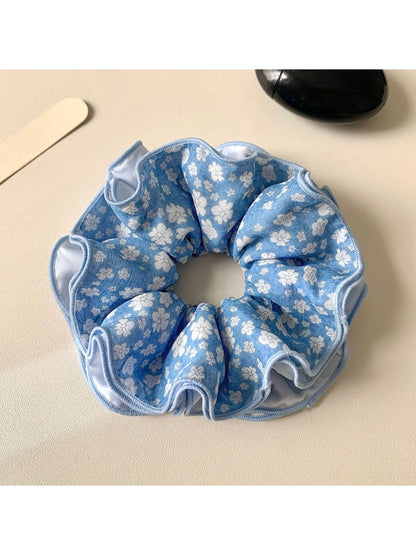 Blue floral pattern scrunchie with pastel colors and gathered fabric design