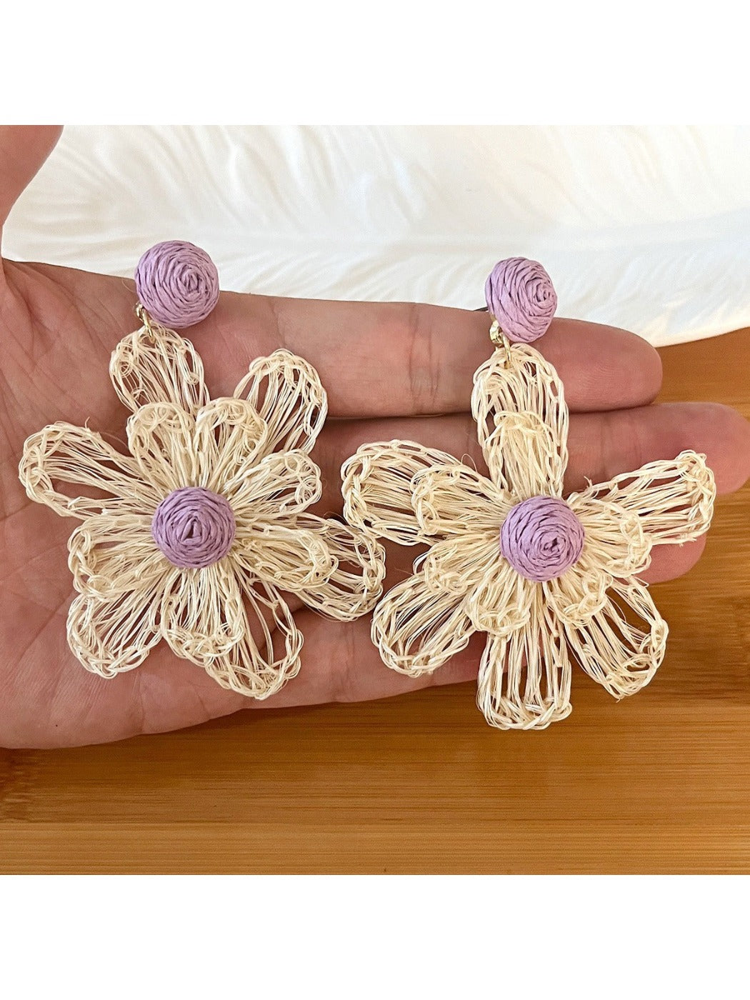 Close-up of earring hook and raffia flower detail on drop earrings