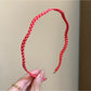 Thin wavy headband displayed flat showing black polka dots on white fabric