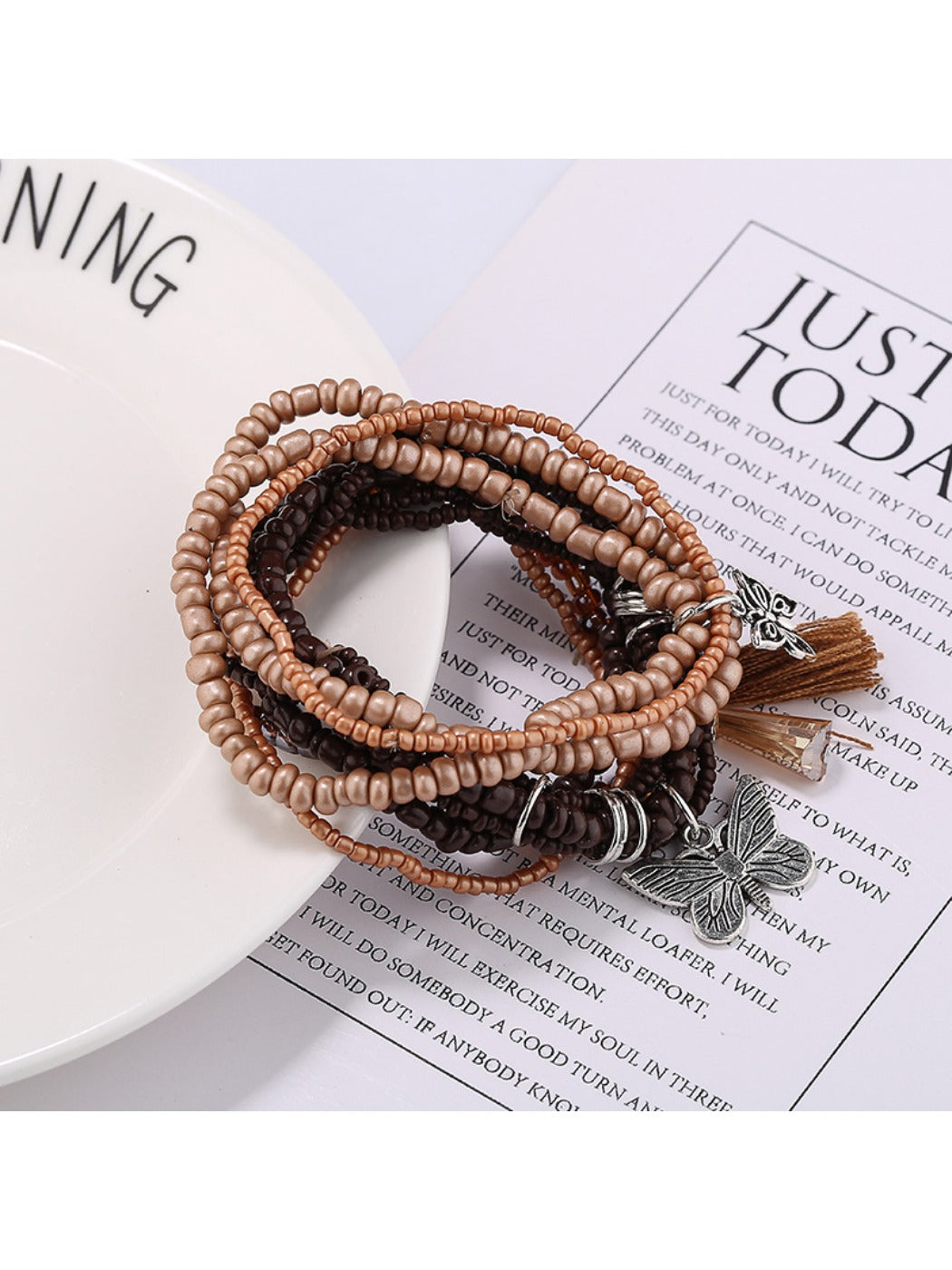 Side view of Lovra butterfly pendant with white and gold beads on bracelet