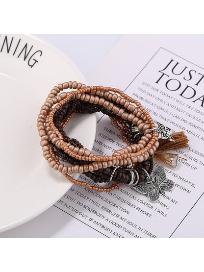 Side view of Lovra butterfly pendant with white and gold beads on bracelet