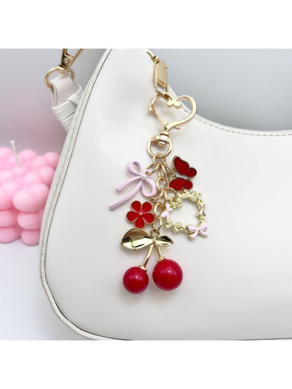 Cherry bow charm keychain hanging from a silver keyring on a white background