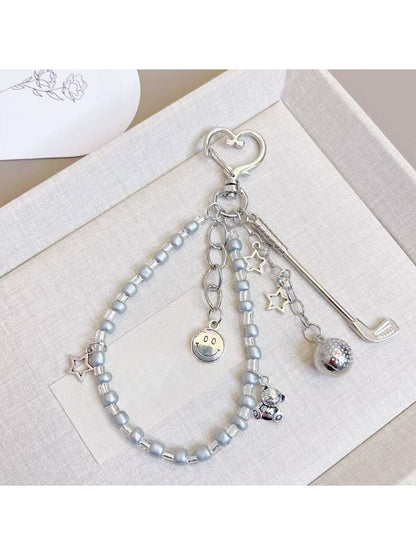 Minimalist golf ball charm keychain with silver ring on white background