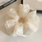Soft beige tulle scrunchie displayed flat highlighting its volume and layers