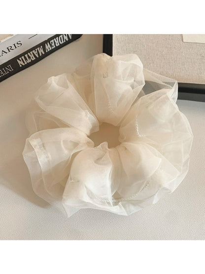 Soft beige tulle scrunchie displayed flat highlighting its volume and layers