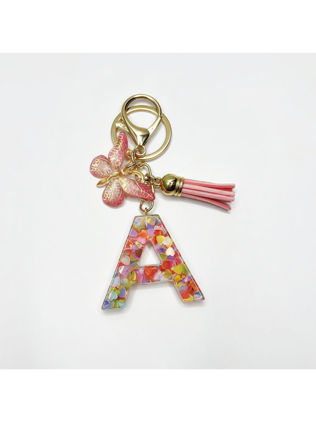 Silver keychain with butterfly and letter pendant next to a notebook
