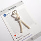 Keypus beaded bow keychain with silver ring held in hand for size reference