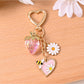 Gold bee keychain hanging from a leather bag strap