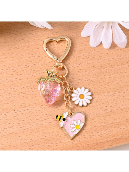 Gold bee keychain hanging from a leather bag strap