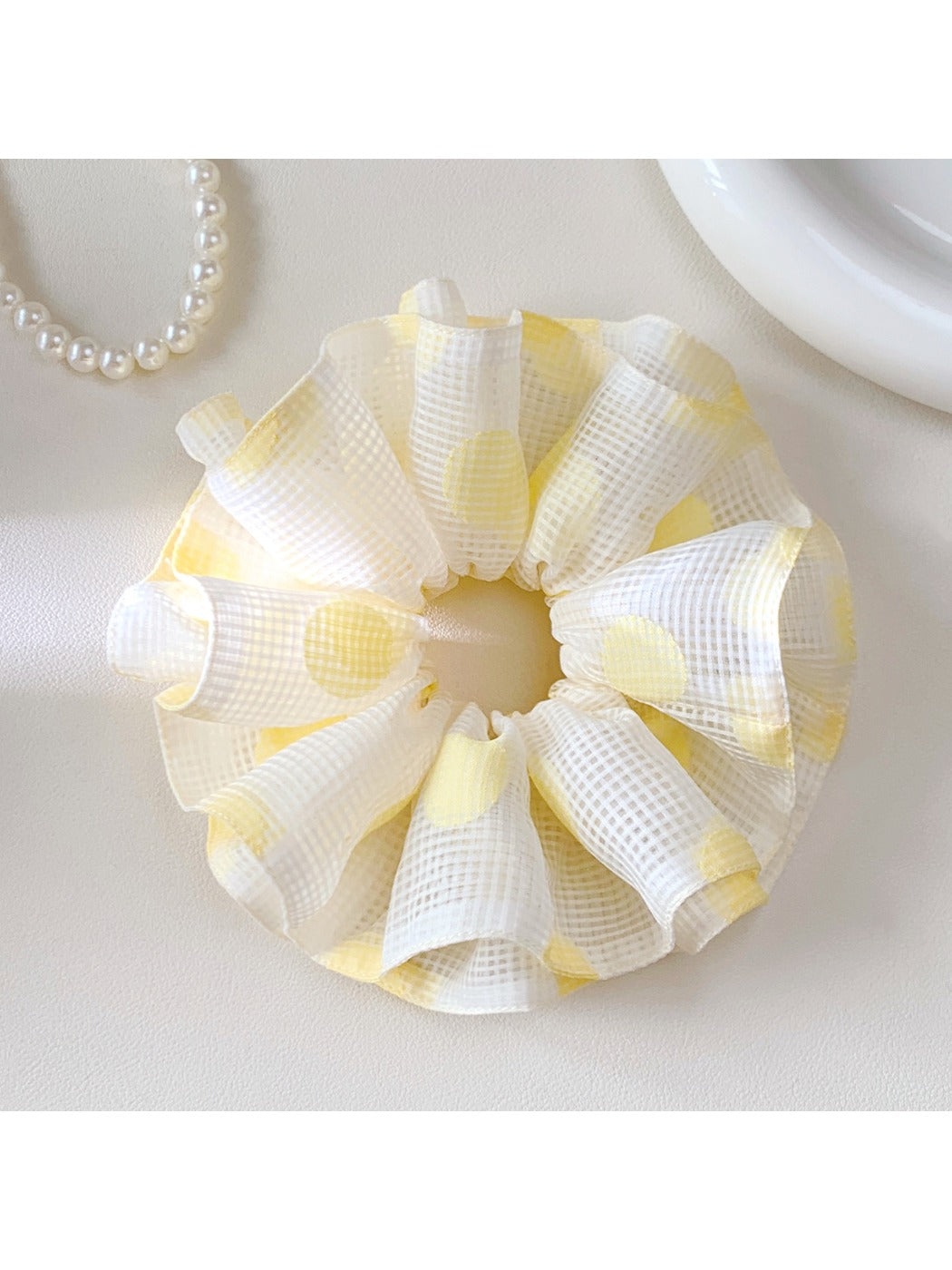 Yellow scrunchie with white polka dots displayed flat
