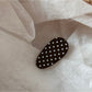 Beau oval polka dot hair clip held in hand showing size and shape