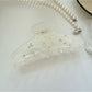 Beau hair claw clip resting on a wooden surface with soft lighting