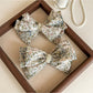 Close-up of Beau Bow Tiny Floral Snap Hair Clip with pink and white flowers on fabric