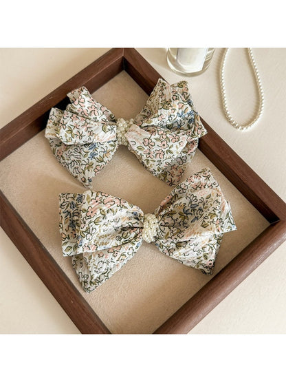Close-up of Beau Bow Tiny Floral Snap Hair Clip with pink and white flowers on fabric