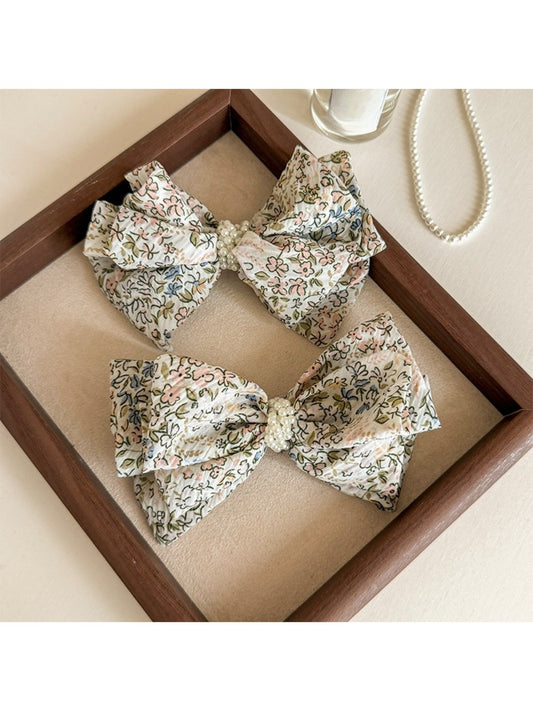 Close-up of Beau Bow Tiny Floral Snap Hair Clip with pink and white flowers on fabric