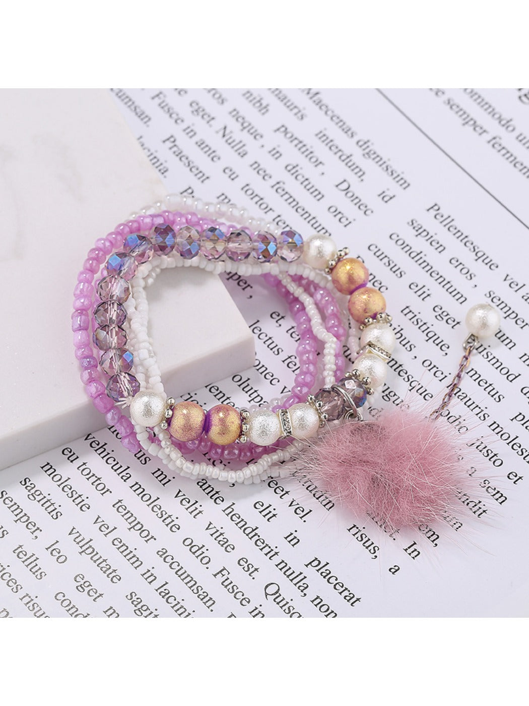 Side view of Lovra pompom pendant bracelet displaying bead arrangement and charm
