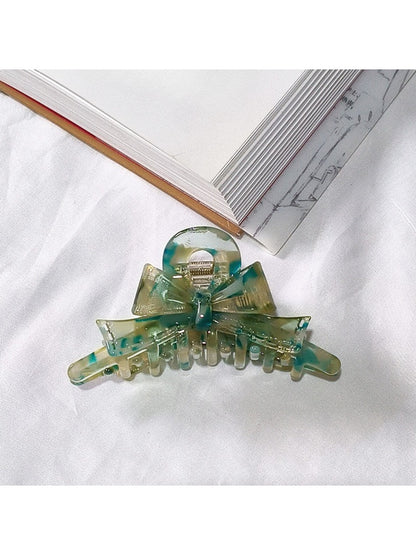 Beau acetate bow shaped claw clip positioned next to matching accessories