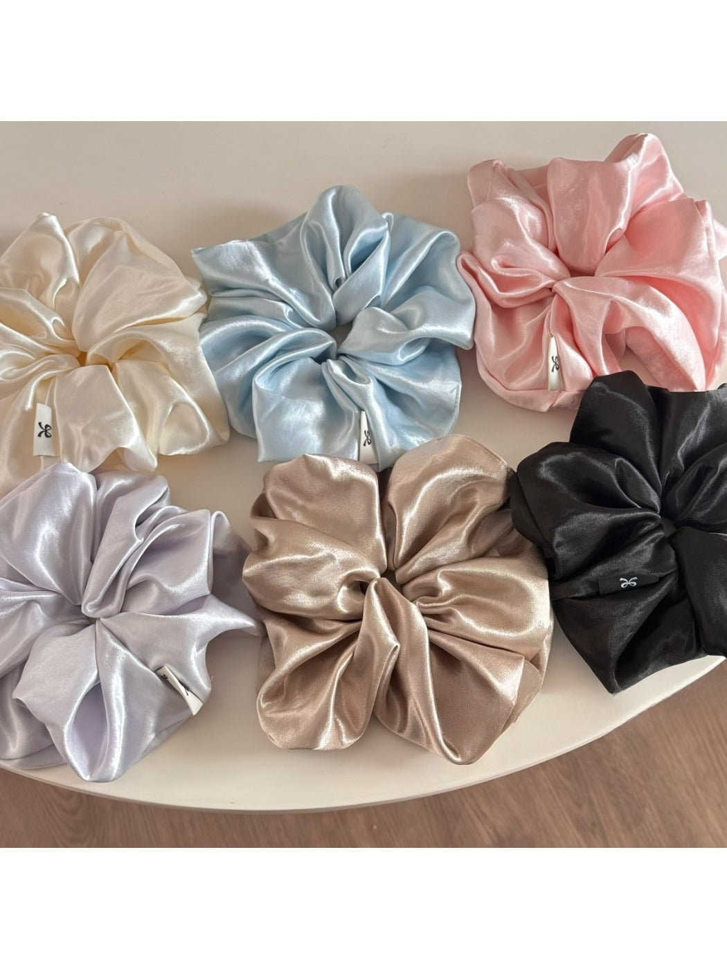 Classic glossy satin scrunchie in soft pink on white background