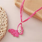 Earedge raffia butterfly pendant necklace displayed on a wooden surface