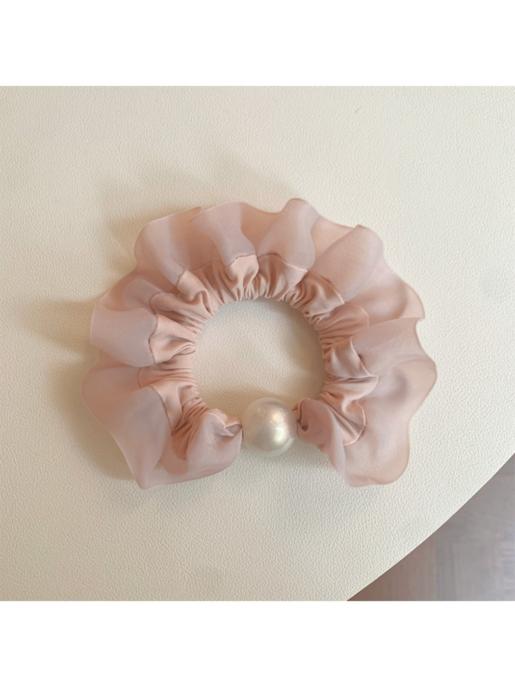 Pink mini scrunchie packaged in a clear plastic bag with branding
