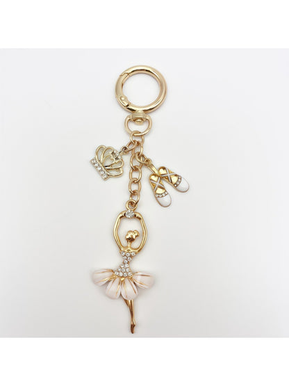 Keychain with ballerina charm next to a smartphone for size comparison