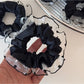 Black scrunchie with white polka dot trim displayed flat