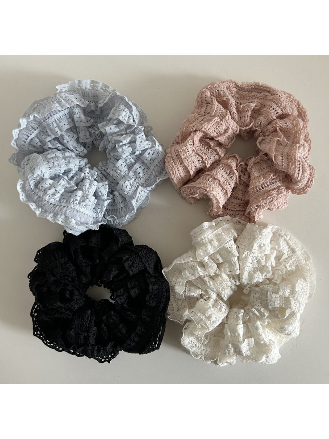 Gifty Sweet Cutout Lace Scrunchie displayed on a wooden surface showing its texture and cutout details