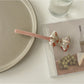 Beau bow bar hair clip placed on wooden surface emphasizing natural acetate texture