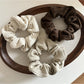Gifty scrunchie wrapped around a ponytail on a model with brown hair