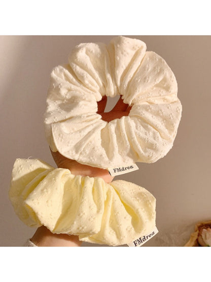 Gifty scrunchie wrapped around a ponytail on a model with natural hair