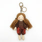 Hand holding fabric yarn doll keychain showing size and scale