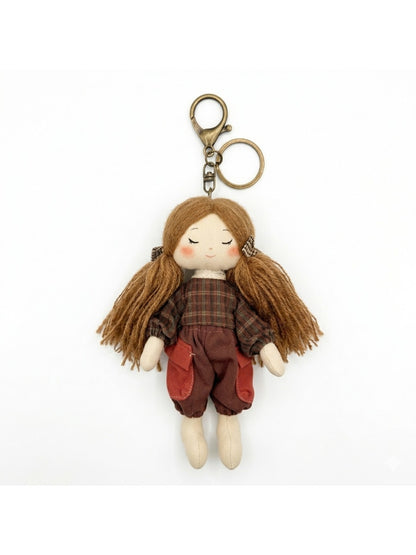 Hand holding fabric yarn doll keychain showing size and scale